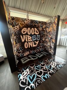 Photo booth backdrop featuring the phrase "GOOD VIBES ONLY" surrounded by colorful heart designs, ideal for event branding and social gatherings.