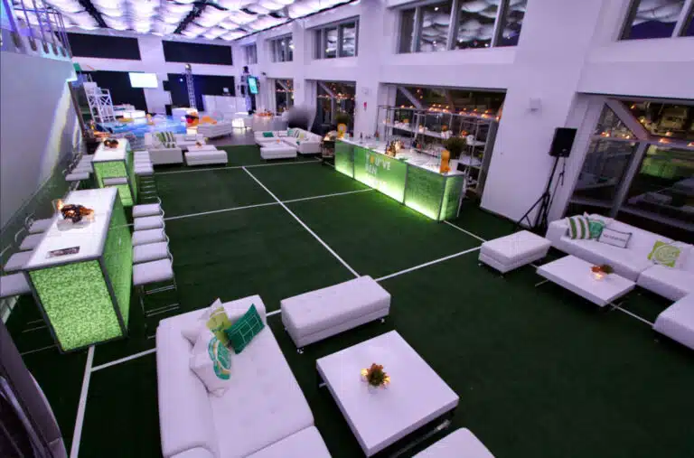 Lounge furniture setup in a modern event space featuring white sofas, green accent tables, and a vibrant atmosphere, ideal for pool party and tennis-themed events, showcasing cost-effective rental options for enhancing guest experiences.