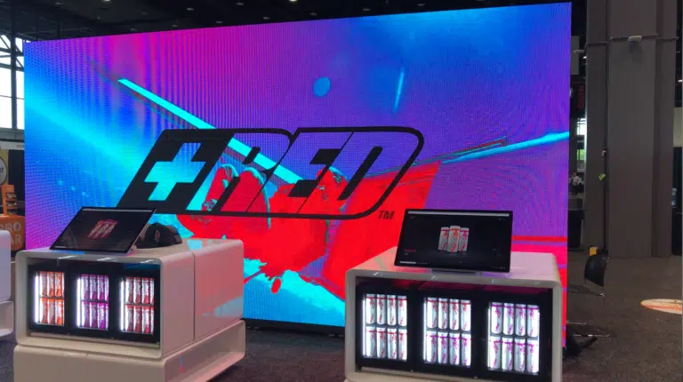 LED video wall display featuring vibrant graphics and branding, with white modular DJ booth setup showcasing beverage coolers, highlighting event rental capabilities for professional audio-visual experiences.