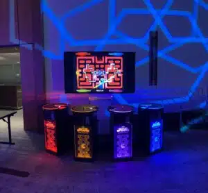 Four-player arcade game setup featuring a colorful Pac-Man display, illuminated with vibrant lighting, ideal for event entertainment rentals.
